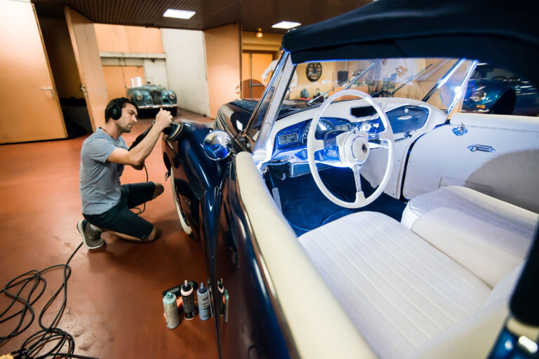 Carrossier perfectionnant les finitions d’un véhicule historique avant un événement VIP.