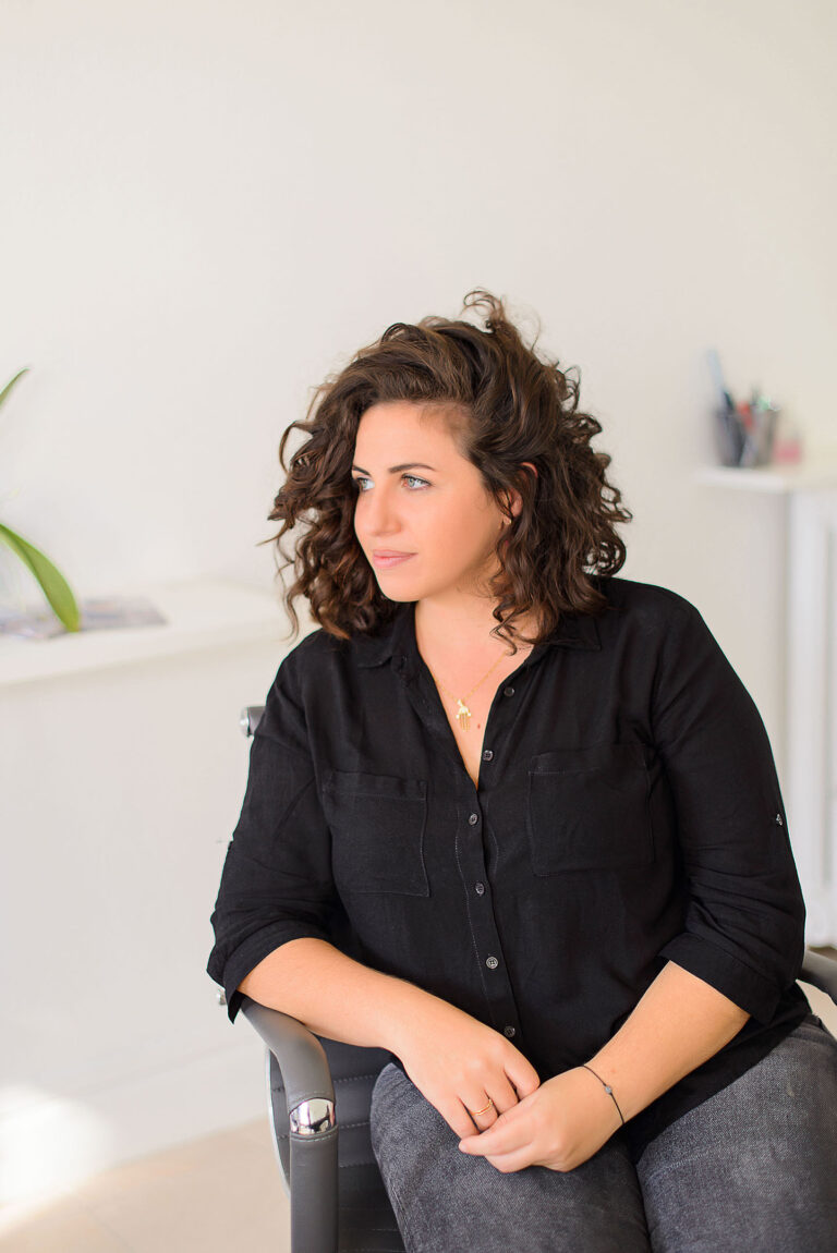Professionnelle du droit assise dans un fauteuil de bureau, regard tourné vers l’extérieur.