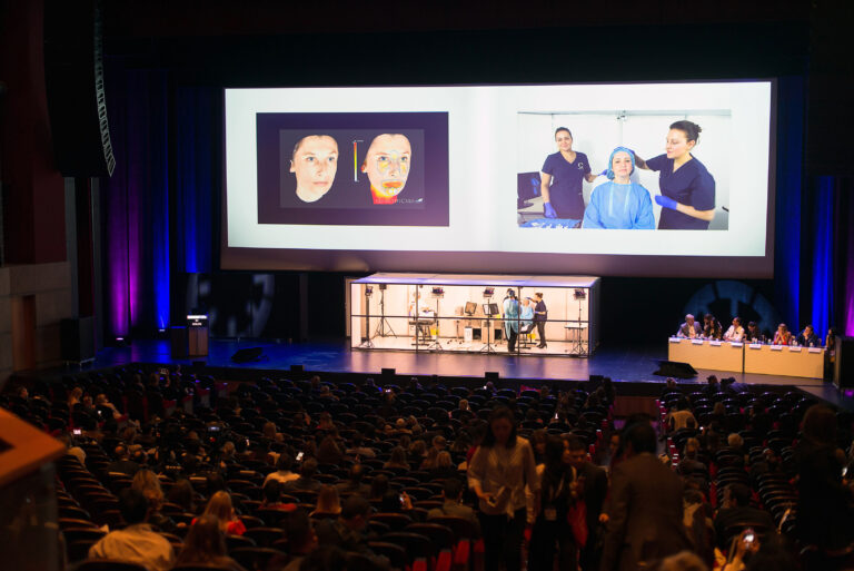 Vue d’ensemble d’une conférence d’entreprise, avec un intervenant présentant un produit high-tech sur écran géant.