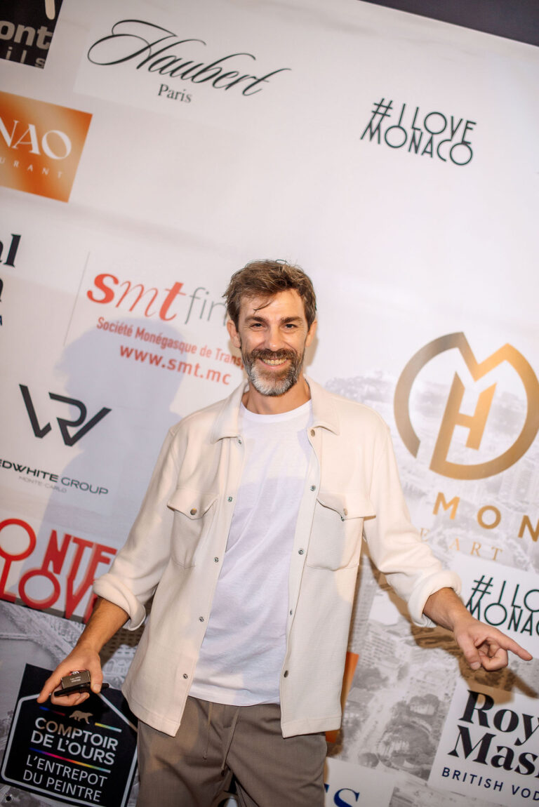 Un artiste rayonnant pose devant le photocall de l’événement.