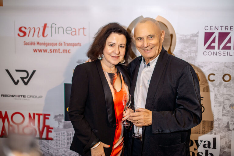 Un couple d’invités pose avec élégance devant le photocall de l’événement.