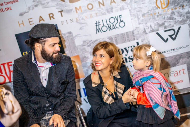 Un artiste échange avec une enfant et sa maman, partageant un moment de découverte et de créativité.