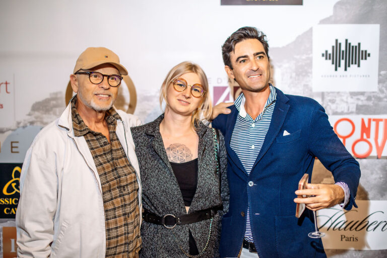 Un trio de passionnés immortalisé devant le mur officiel du vernissage.