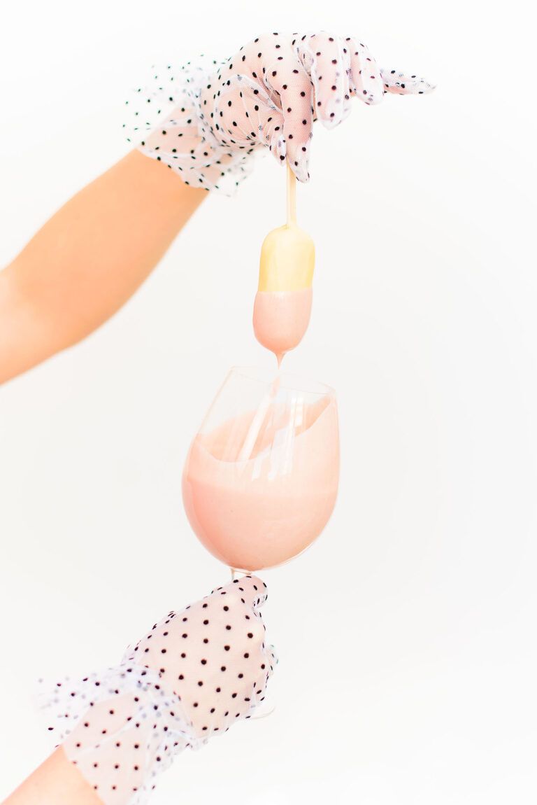 Zoom sur des mains appliquant un nappage au chocolat sur un dessert sur bâton.