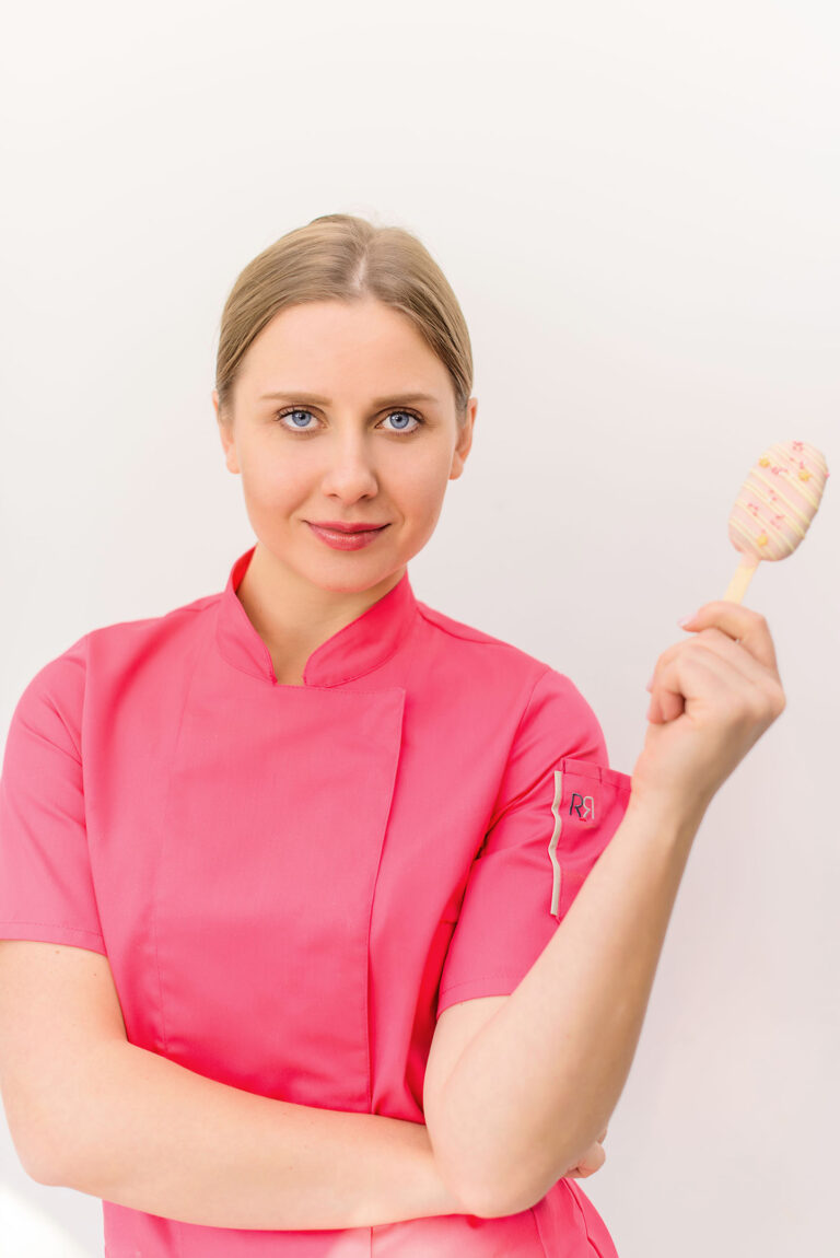 Portrait gourmand : une pâtissière souriante tenant un dessert nappé de chocolat.
