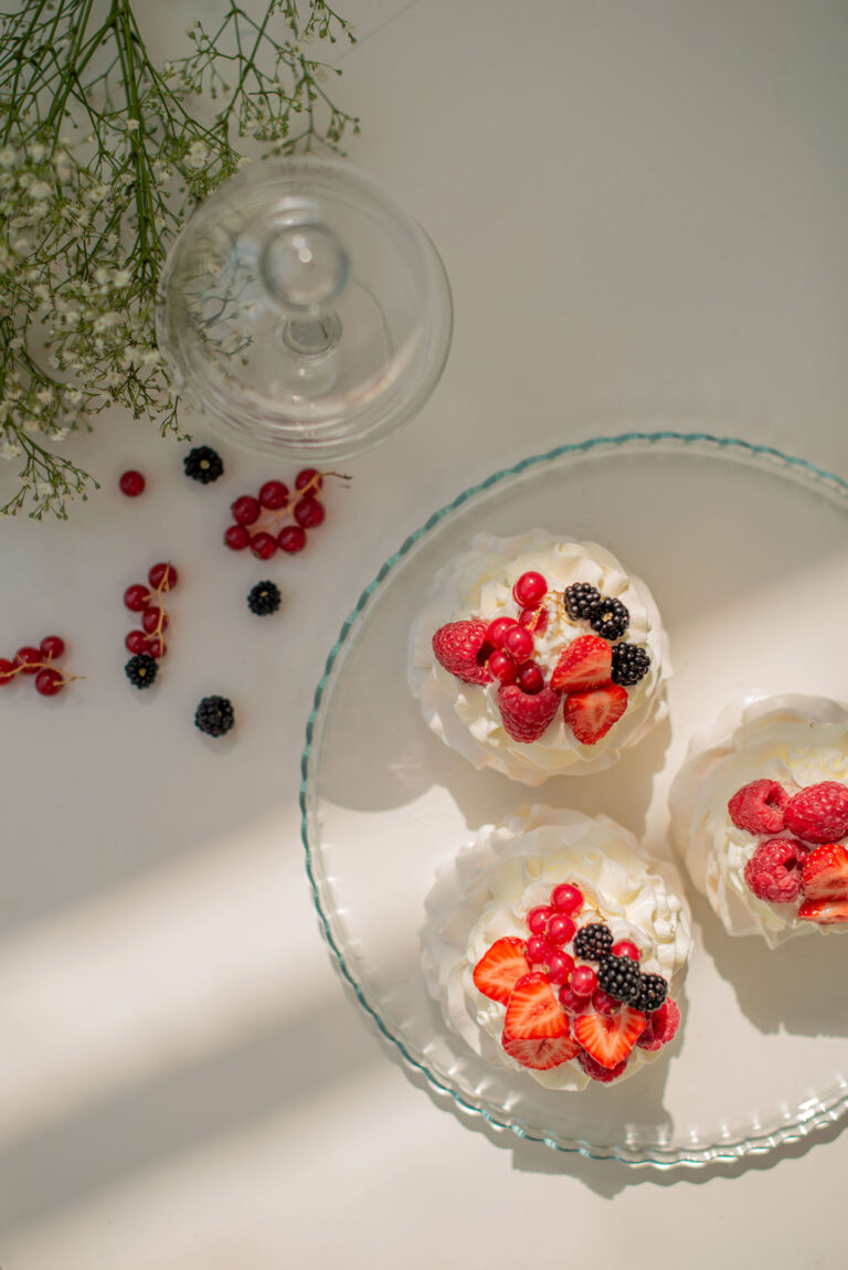 Vue du dessus d’une Pavlova garnie de fruits, capturant chaque détail gourmand.