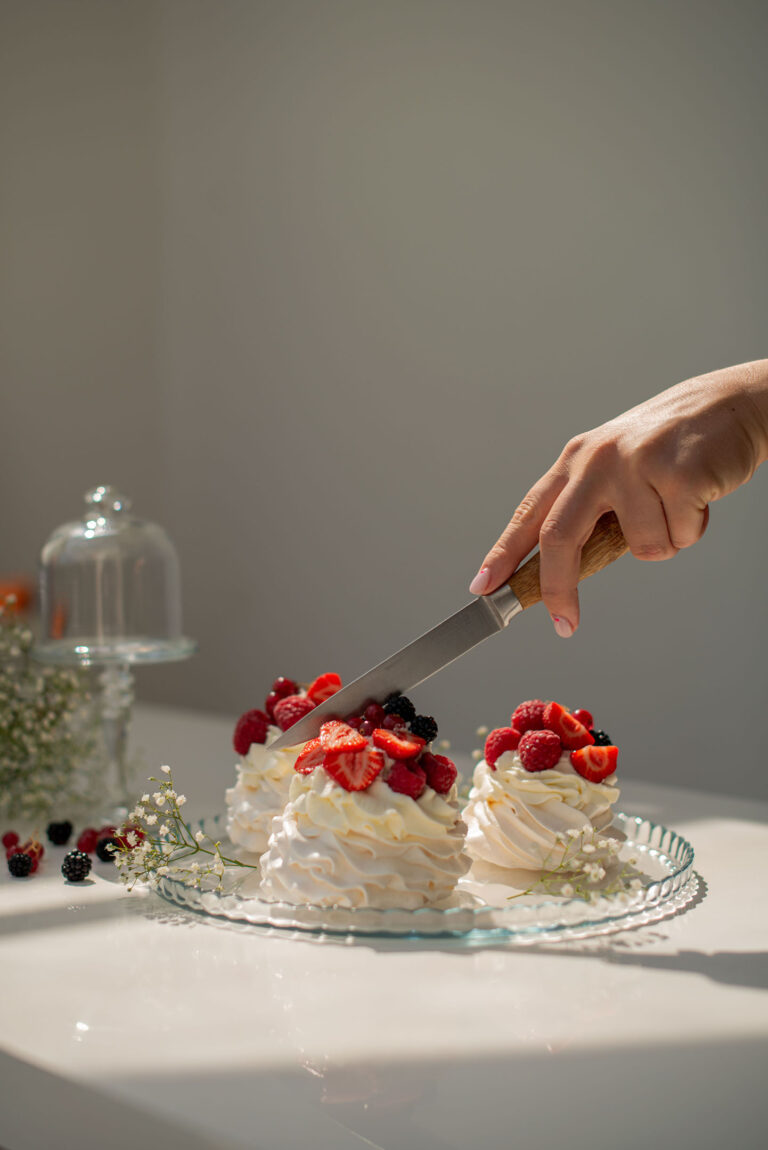 Découpe d’une Pavlova aérienne, capturant sa texture légère et gourmande.