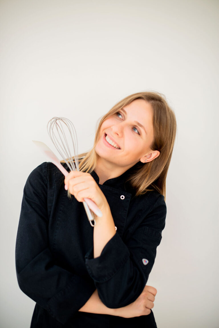 Ustensiles en main, sourire aux lèvres : une pâtissière passionnée en pleine création.