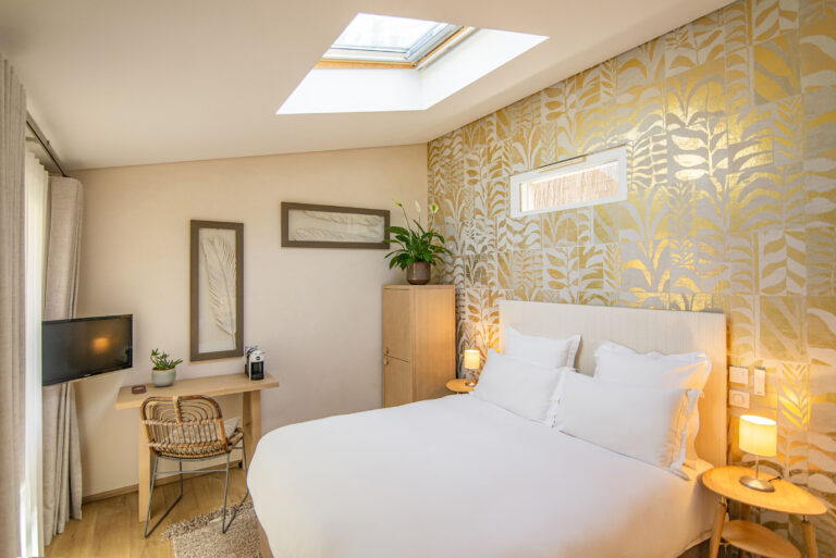 Lit moelleux et mobilier en bois clair dans une chambre d’hôtel élégante et contemporaine.