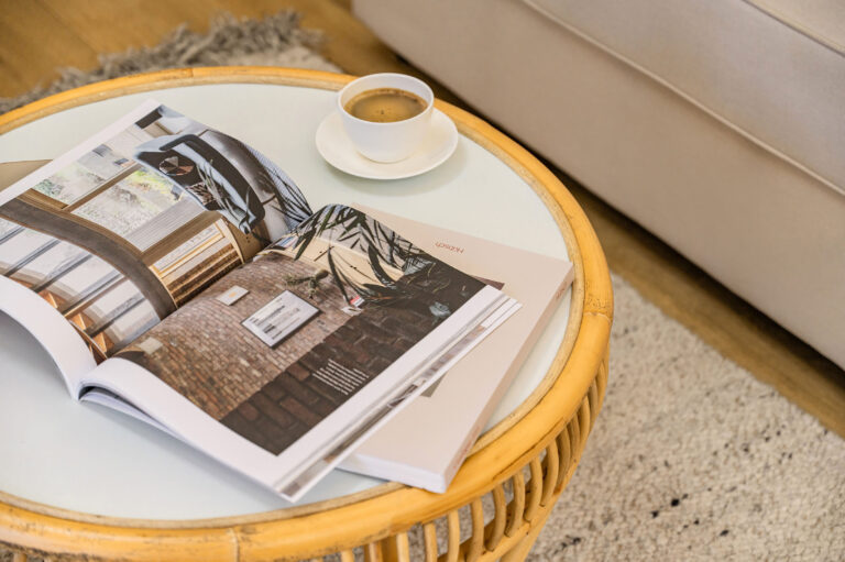 Table basse avec catalogue d’hôtel et ambiance méditerranéenne.