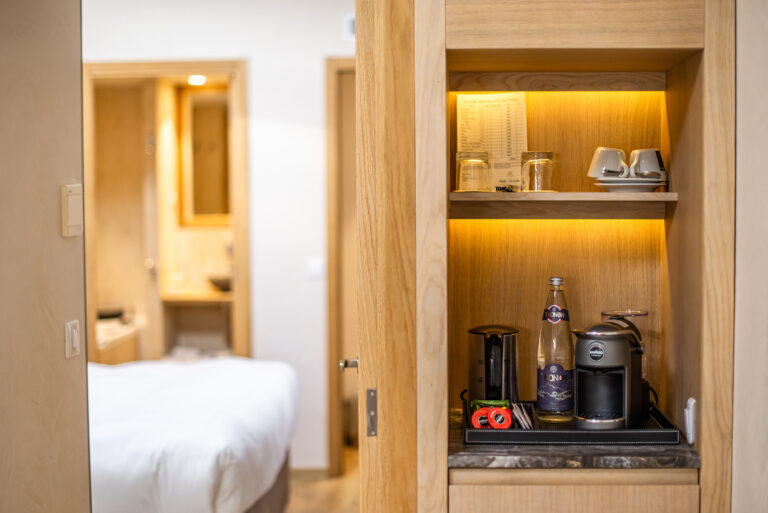 Mini bar et espace café en chambre – Machine à café haut de gamme et assortiment de tasses élégantes pour un séjour premium.