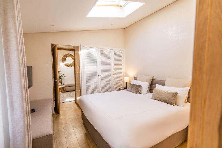 Ambiance douce d’une suite élégante – Décoration minimaliste et chaleureuse avec mobilier en bois et linge de lit soigné.