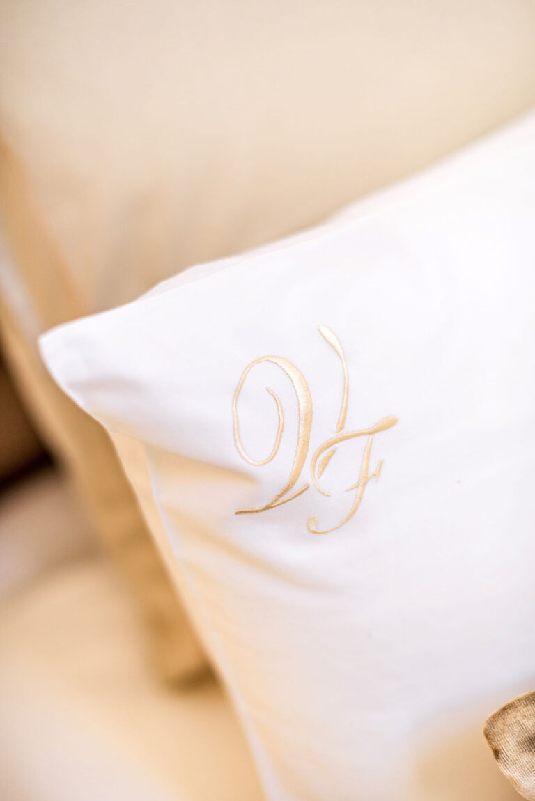 Plan rapproché sur le logo de l'hôtel brodé sur l'oreiller, une attention particulière accordée aux détails.
