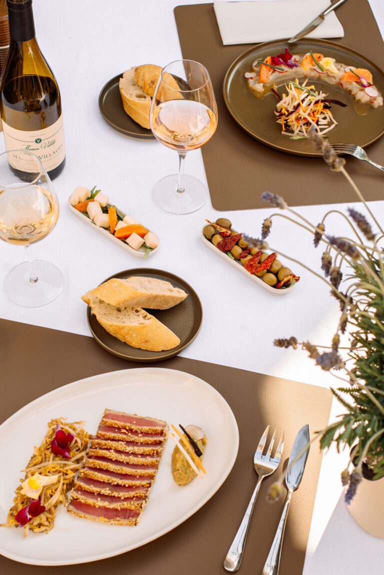 Vue du dessus : assiette gastronomique, amuse-bouches et vin en terrasse.