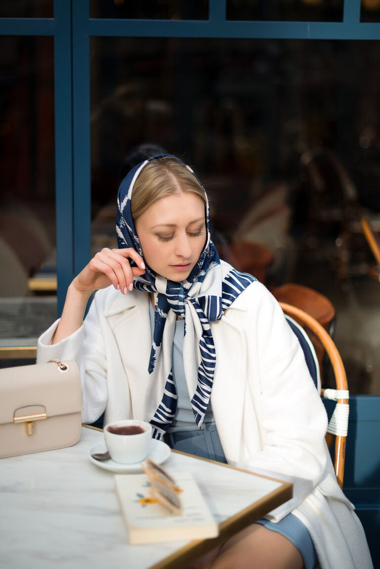 Portrait mode et lifestyle à Nice : femme posant avec élégance sur une table de café, tons bleus et beiges.