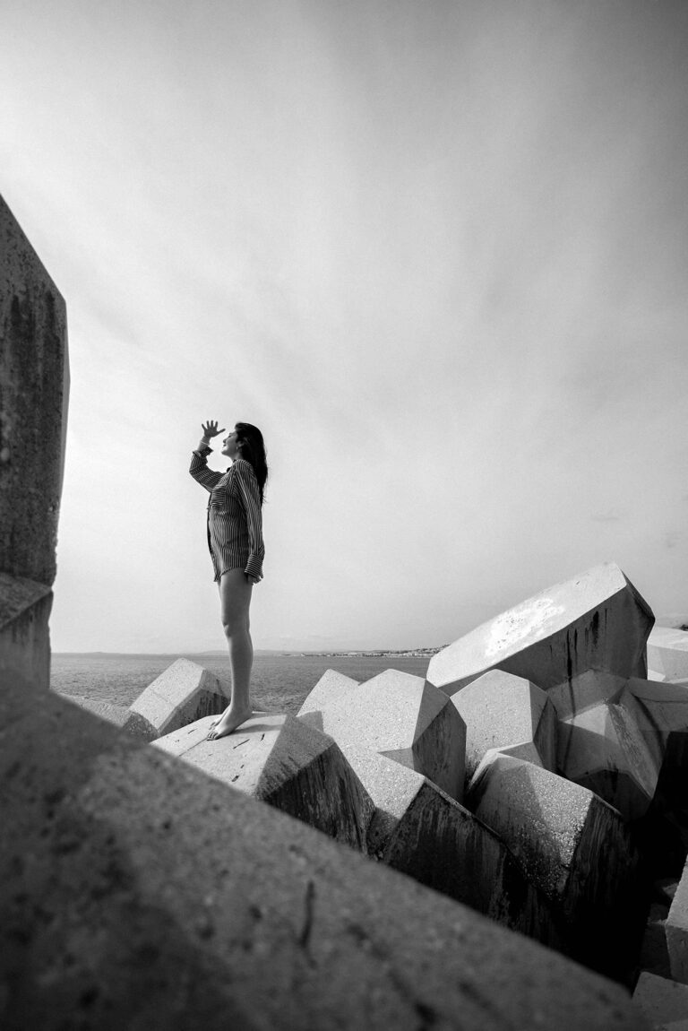 Photographe portrait artistique Nice : une femme pose sur une digue face à l’horizon.