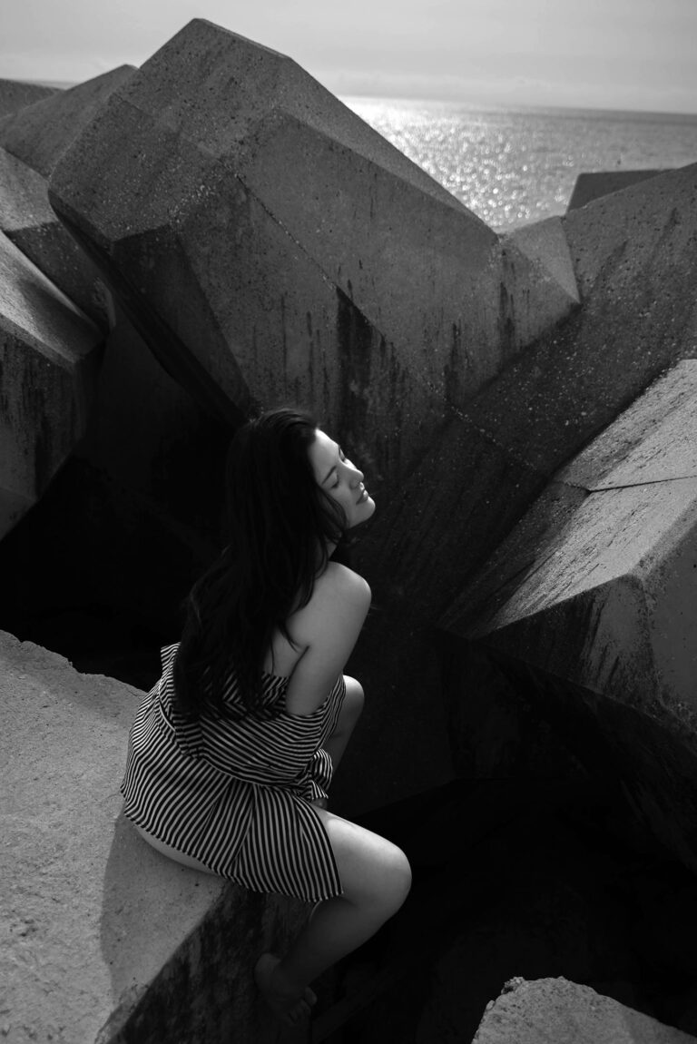 Portrait artistique en noir et blanc à Nice, une femme pose sur des blocs de béton.