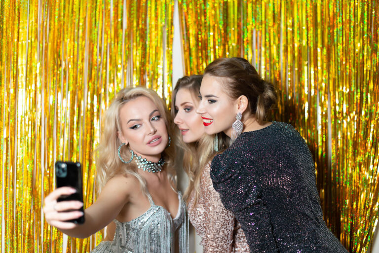 Selfie entre amies – Éclats de rire et poses spontanées devant le rideau scintillant.