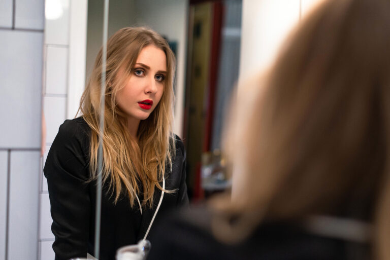 Séance maquillage dans la salle de bain – Portrait glamour d’une amie devant le miroir.