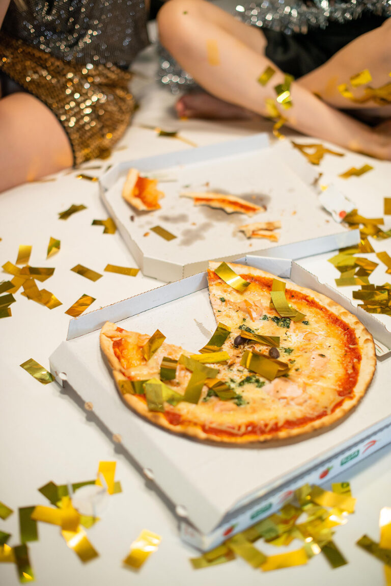 Détail festif Nice : pizza et confettis dorés, symbole d’une nuit entre amies aussi savoureuse que brillante.