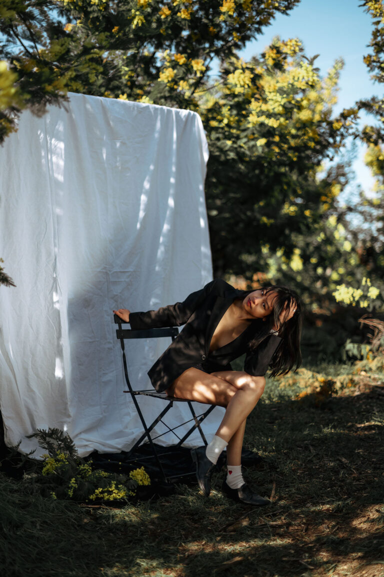 Photographe portrait créatif Alpes-Maritimes : modèle entre fond noir et végétation luxuriante.