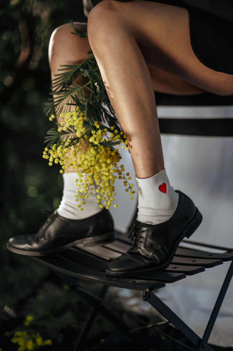 Photographe mimosa Côte d’Azur : détail de chaussures et chaussettes blanches avec branche de mimosa