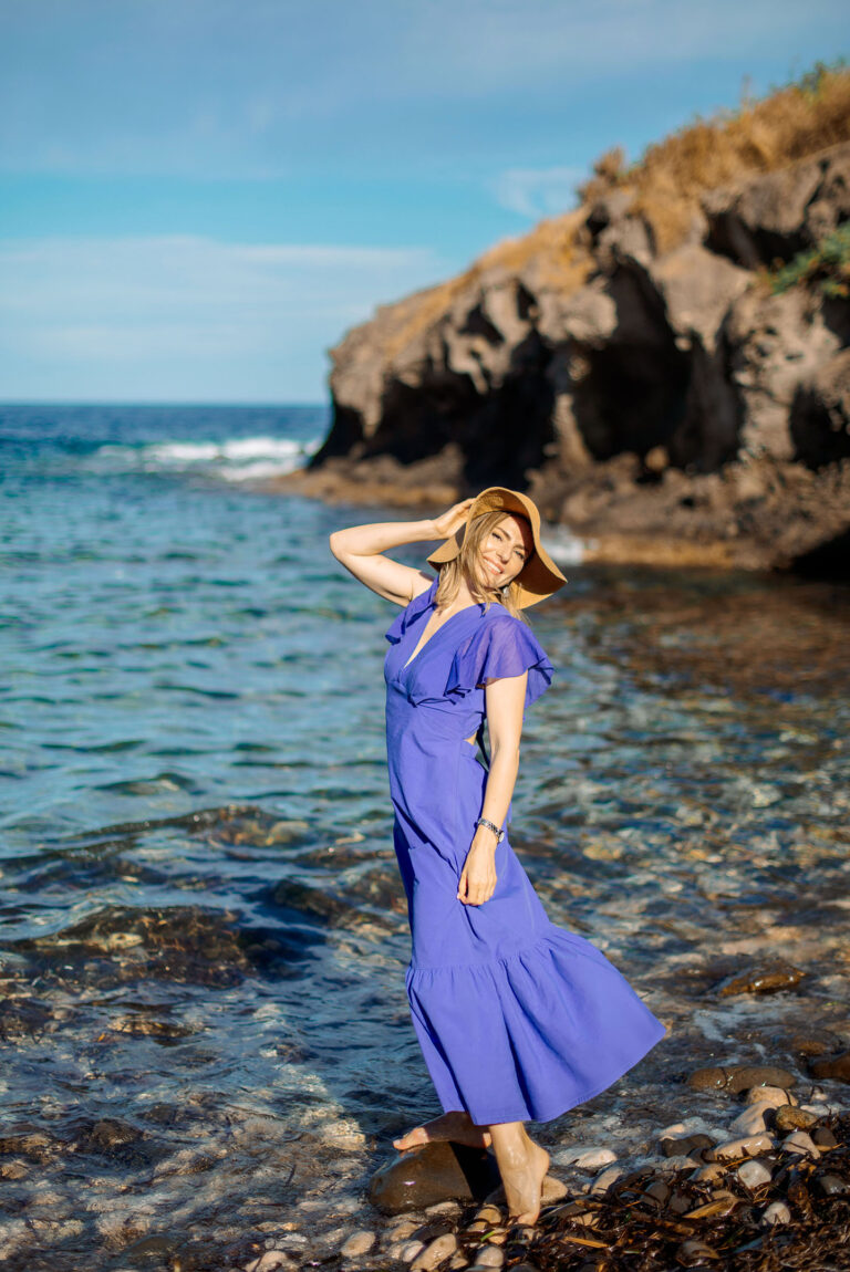 Photographe portrait Côte d’Azur : femme posant pieds dans l’eau devant les falaises.