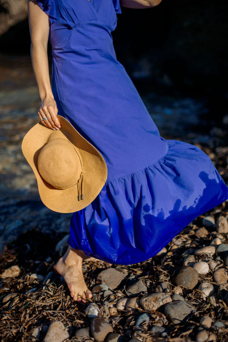 Détail: femme en bord de mer avec panier en osier et chapeau en paille.