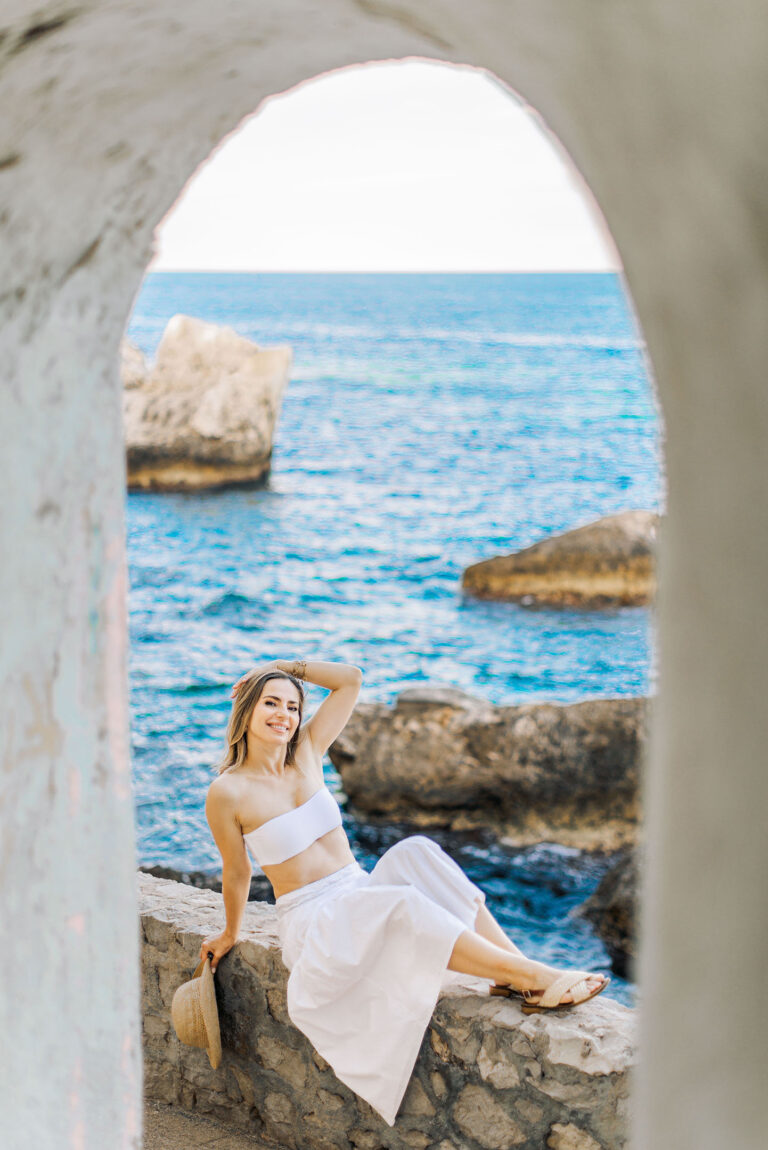Détente en plein air : portrait féminin sur un muret surplombant la Méditerranée.