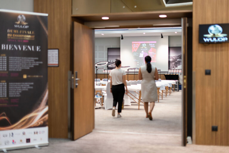 Deux organisatrices pénétrant dans la salle, finalisant les préparatifs avant le début du concours.
