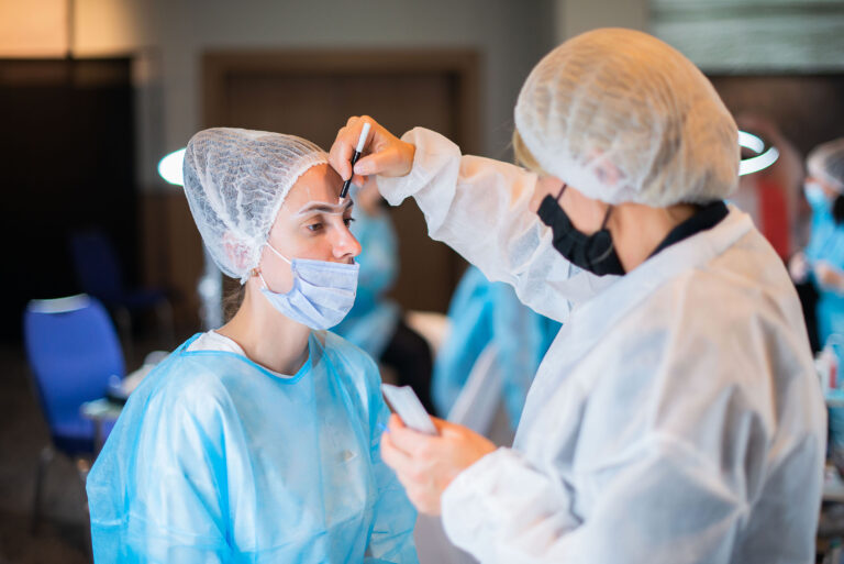 Modèle assise pendant que la participante trace le contour des sourcils avec précision.