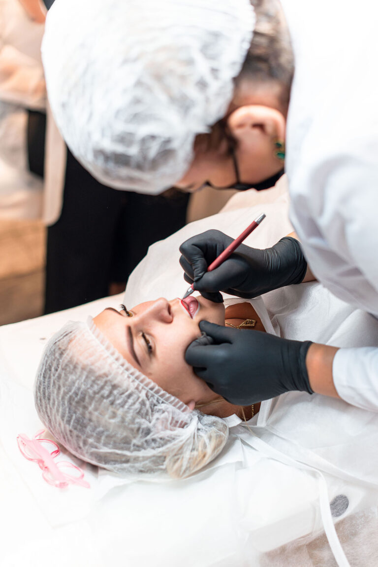 Gros plan sur les mains d'un artiste réalisant un maquillage permanent des lèvres.