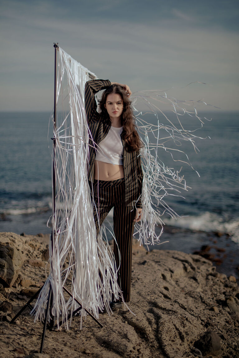 Portrait créatif sur la falaise, voile blanc dans le vent – séance artistique entre ciel et mer.