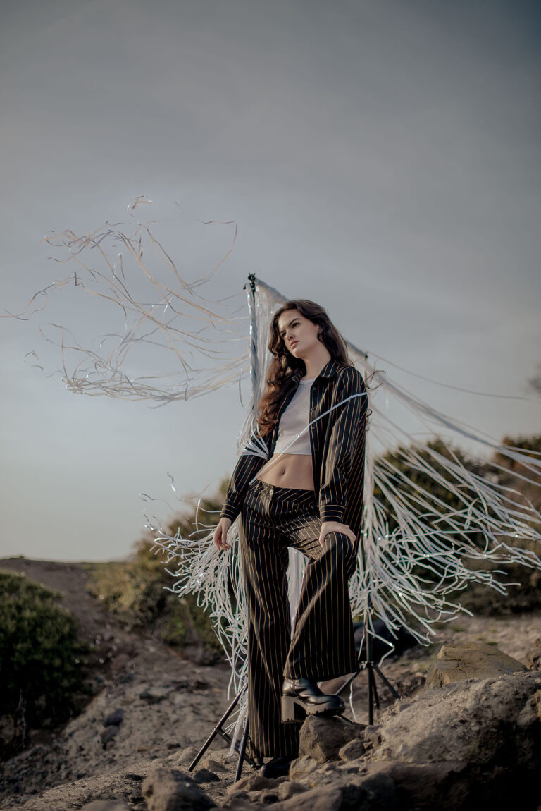 Photographe à Cap d’Ail – modèle en mouvement derrière un rideau de lanières blanches, effet poétique garanti.