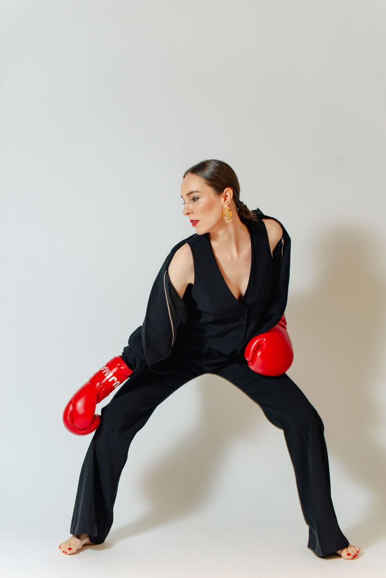 Shooting dynamique d'une femme en costume avec accessoires de boxe.