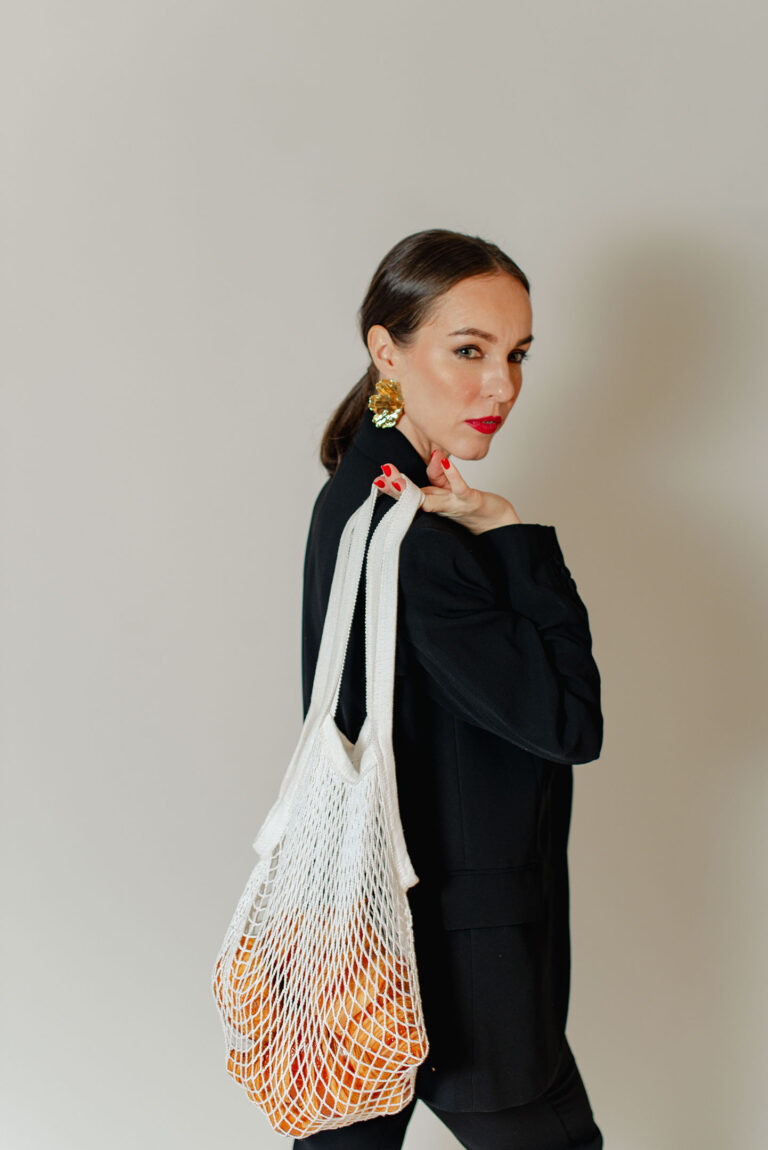 Tatiana pose en tenant un sac filet plein de croissants dans un studio photo.